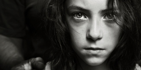 Girl facing camera with someone's hands on her shoulder symbolizing Parental Kidnapping